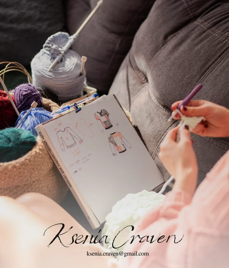 Designer's hands crocheting next to a notebook with sweater sketches and colorful yarn in a cozy freelance artist studio.
