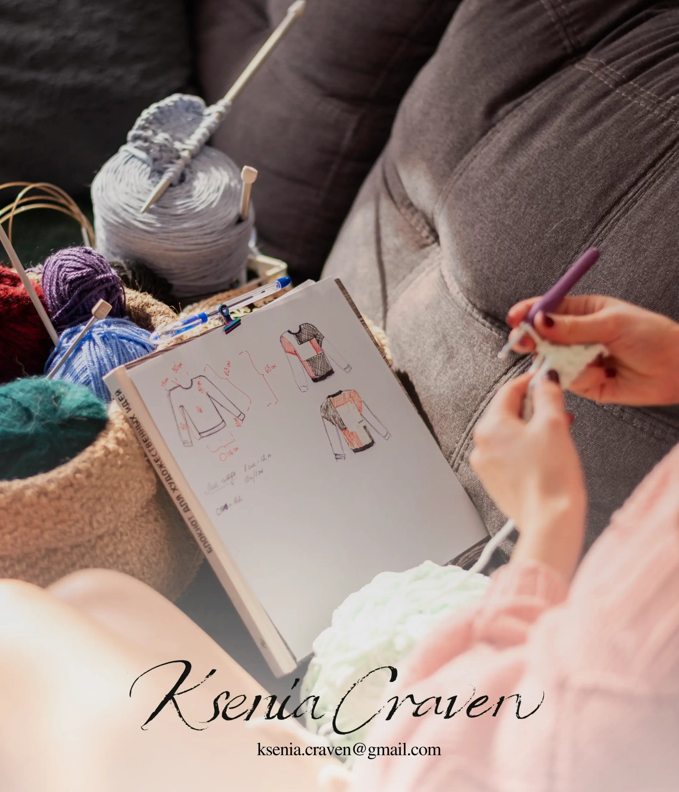 Designer's hands crocheting next to a notebook with sweater sketches and colorful yarn in a cozy freelance artist studio.
