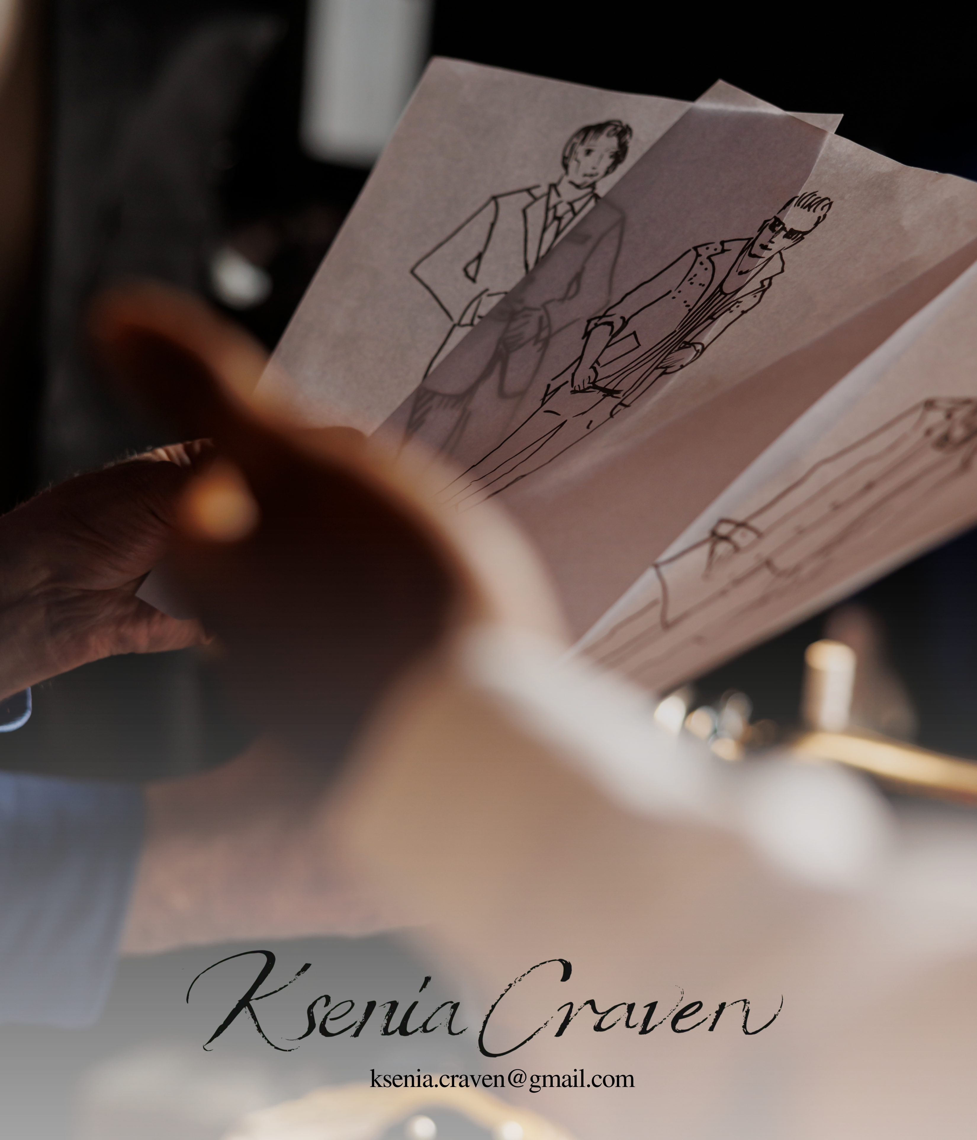 Hands holding translucent fashion sketches of men's suits by Ksenia Craven, featuring elegant line art.