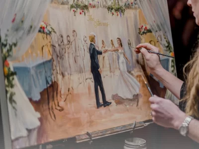 Live wedding painter Ksenia Craven adding details to a custom canvas painting of a bride and groom’s first dance.
